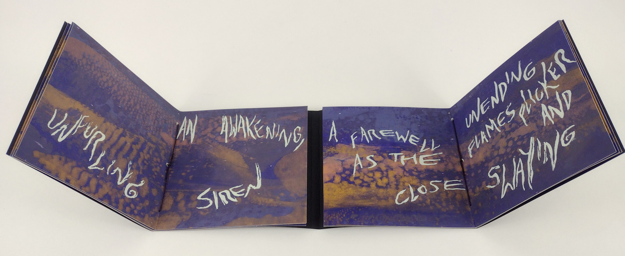 an open artist's book is screenprinted with text reading, "an awakening, unfurling siren / a farewell unending as the flames flicker and close swaying"